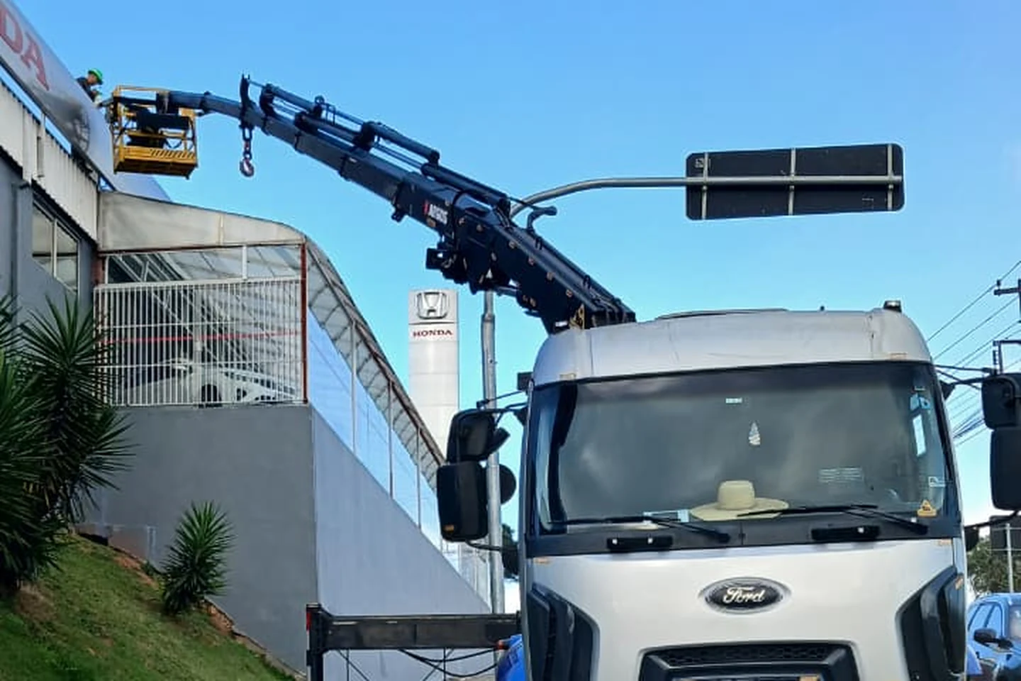 Caminhão munck da CLF com cesto aéreo em manutenção de fachada comercial