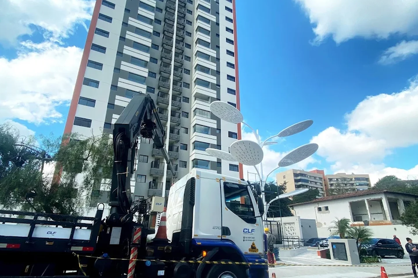 Caminhão munck da CLF posicionado em frente a um edifício residencial alto