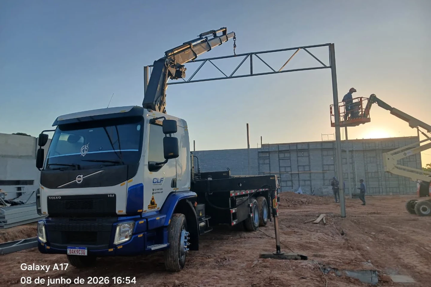 Caminhão munck da CLF posicionando uma viga treliçada em montagem de estrutura metálica